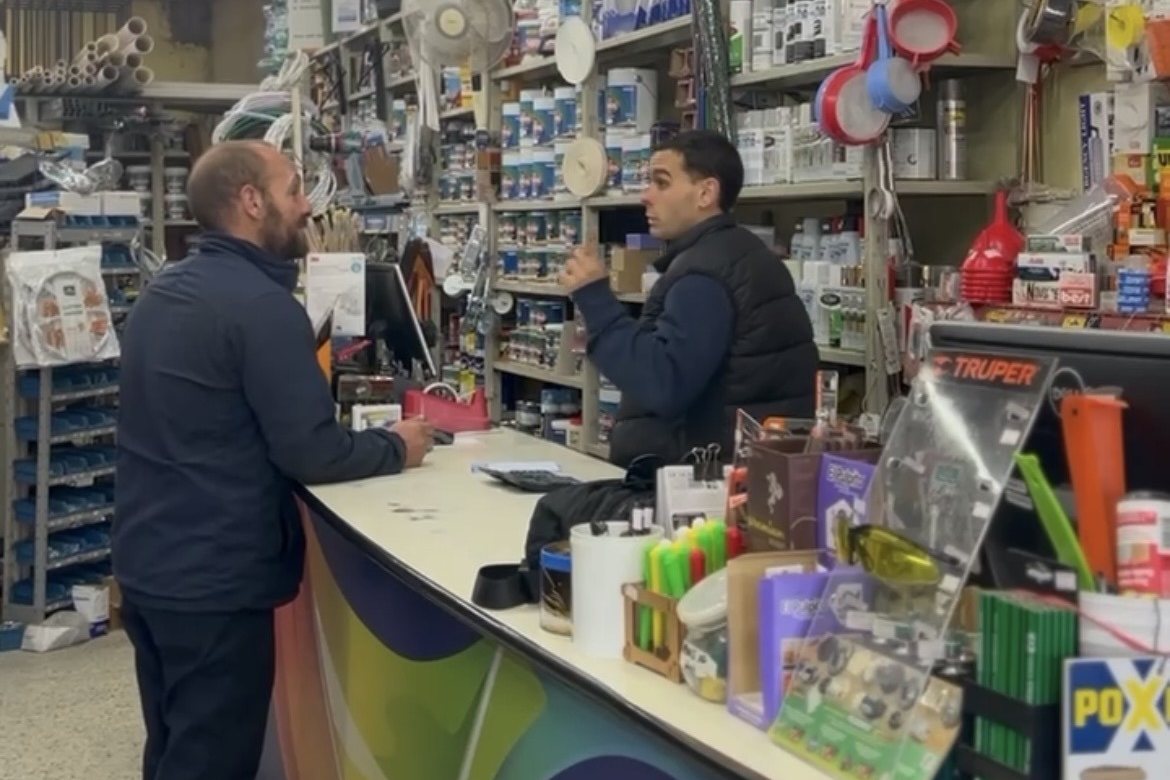 Diego atendiendo a un cliente en el mostrador de Propios, con las góndolas del local detrás